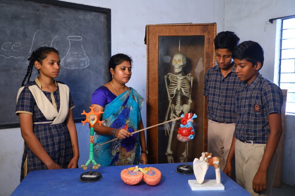 A teacher helps a student work in a Biology lab in a well-lit classroom.